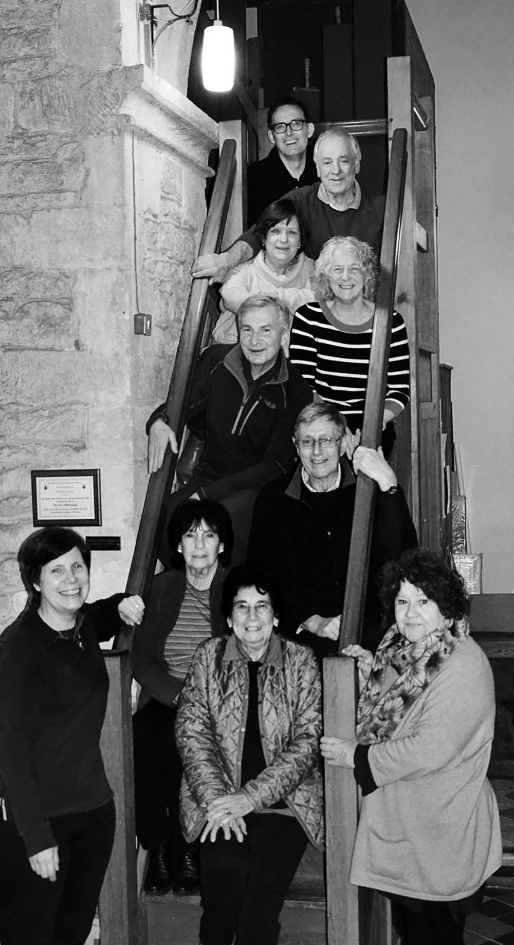 10 people gathered for a group photo, sitting and standing on a steep staircase in the church.