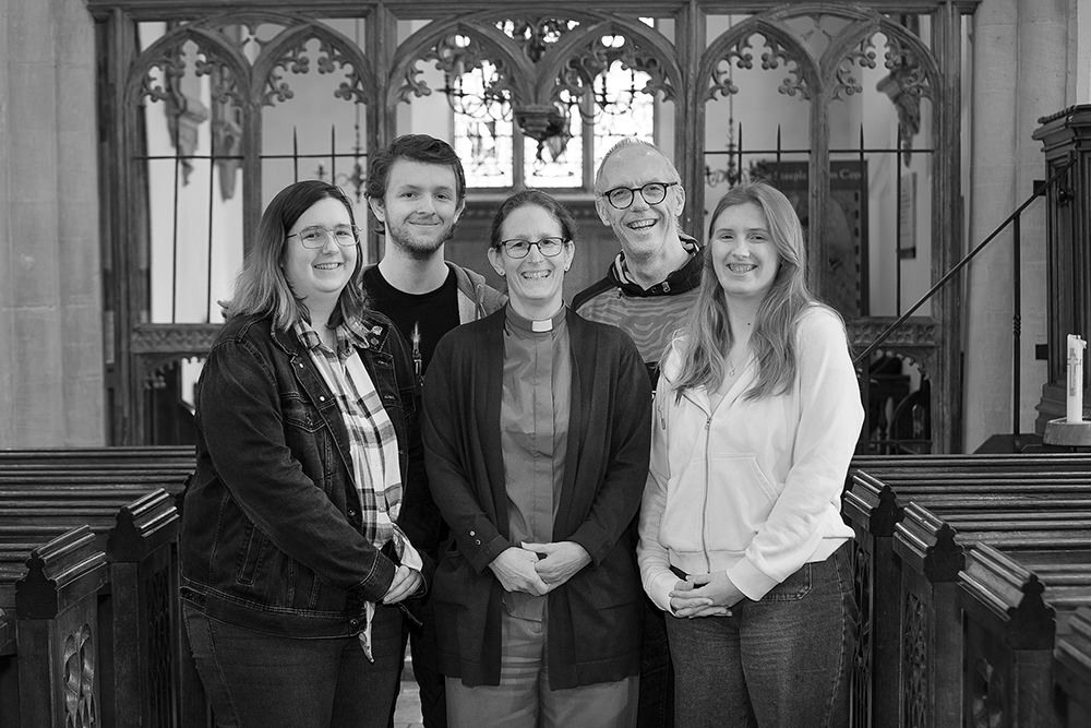 Portrait of five people standing in a group inside a church.