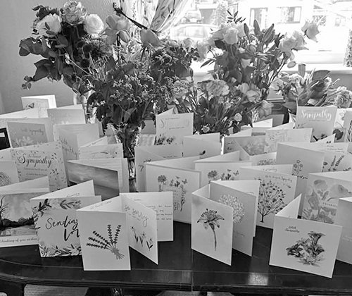 Vases of flowers and dozens of cards arranged on a table.
